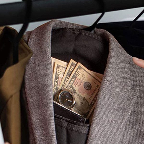 Suit jacket with cash and a wristwatch in the pocket, hanging in a closet.