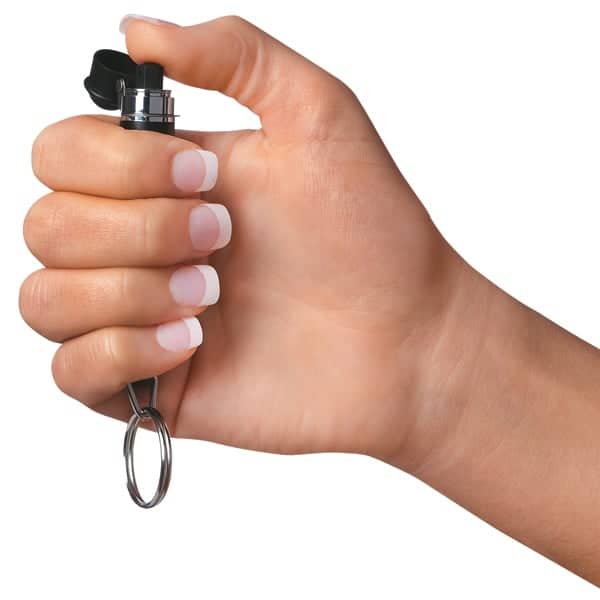 Hand holding a small black keychain with a metallic ring on a white background.