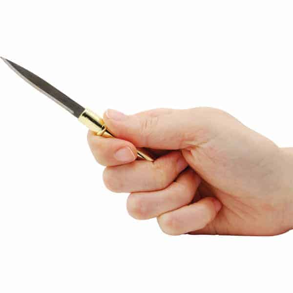 Hand holding a small folding knife with a golden handle against a white background.