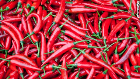 A pile of fresh red chili peppers with green stems, ideal for spicy cooking and seasoning.