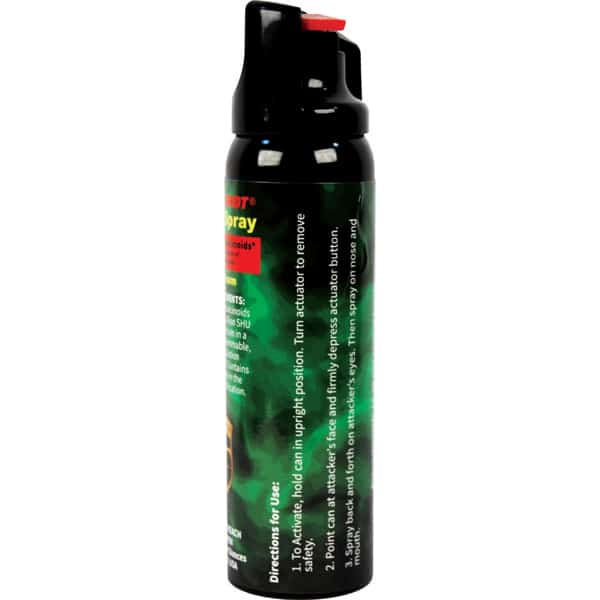 Black pepper spray can with green label and red safety cap, showing usage directions for self-defense.