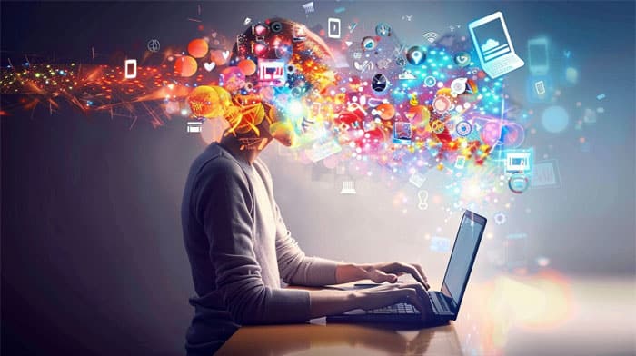 Person at laptop with colorful digital concepts flowing out, symbolizing creativity and digital thinking.