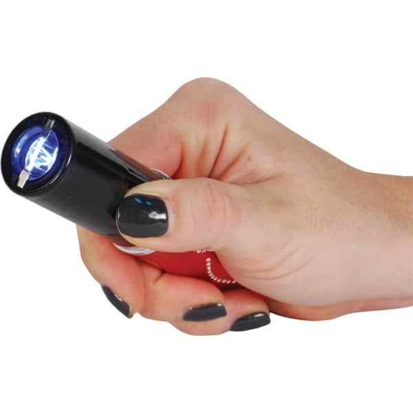 Hand holding a small black flashlight with glowing blue light.